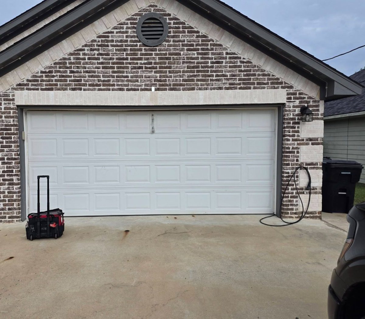 White residential garage door closed on a brick house